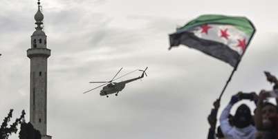 Helicóptero militar lança flores e confetes sobre multidão comemorando os dez anos da vitória de forças rebeldes sobre o exército de Bashar al-Assad em Idlib, Síria, em 28 de março de 2025. Foto: © Ghaith Alsayed / АР / RFI